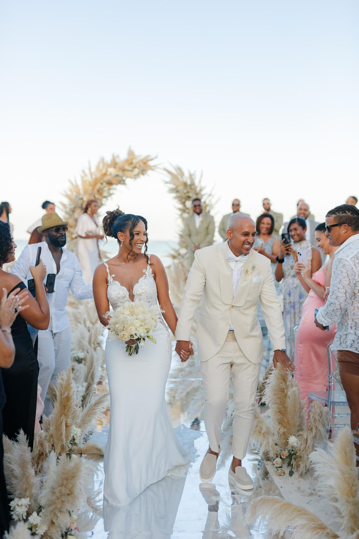 A beach ceremony under a floral arch